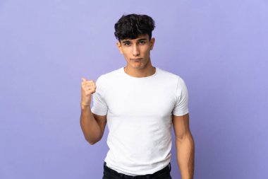 Arjantinli genç adam arka planda izole edilmiş mutsuz ve kenarı işaret ediyor.