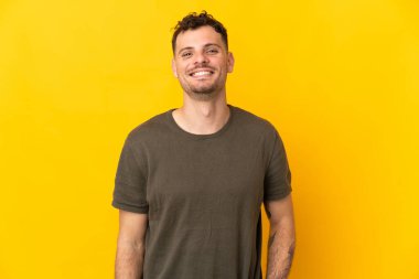 Sarı arka planda izole edilmiş genç beyaz yakışıklı adam gülüyor.