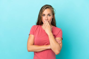 Mavi arka planda izole edilmiş genç beyaz kadın sağa bakarken şaşırdı ve şok oldu.