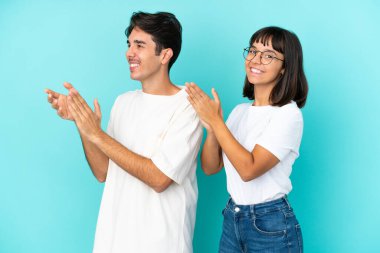 Genç melez çift mavi arka planda bir konferansta sunumdan sonra alkış tutuyorlar.