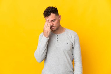 Sarı arka planda yalnız ve başı ağrıyan beyaz, yakışıklı bir genç.