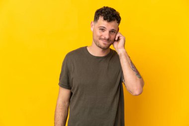 Sarı arka planda izole edilmiş genç beyaz yakışıklı adam gülüyor.