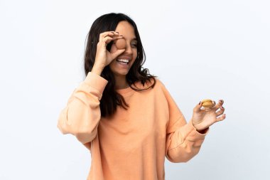 Soyutlanmış beyaz arka planı olan genç bir kadın renkli Fransız badem kurabiyeleri tutuyor.