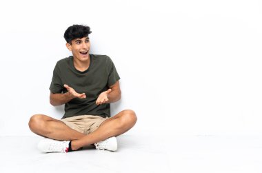 Genç Arjantinli adam yerde oturuyor ve yüzünde sürpriz bir ifade var.