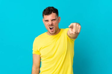 Kafkasyalı yakışıklı adam mavi arka planda izole edilmiş hayal kırıklığına uğramış ve ön tarafı işaret ediyor.