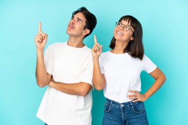 Mavi arka planda soyutlanmış genç melez çift harika bir fikre işaret ediyor ve araştırıyor.