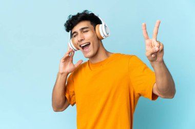 Arjantinli genç adam arka planda izole edilmiş müzik dinliyor ve şarkı söylüyor.