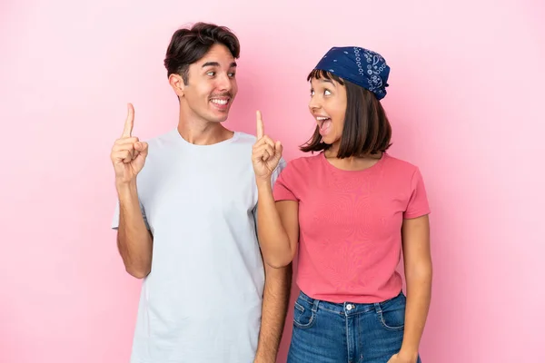 在粉色背景下分居的一对年轻夫妇想在举起一只手指头的同时实现这个解决方案 — 图库照片