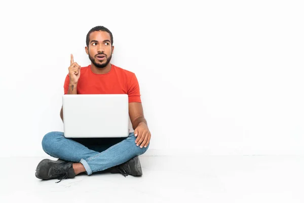 厄瓜多尔年轻人 拿着笔记本电脑坐在地板上 与白色背景隔离 想着用手指指尖 — 图库照片