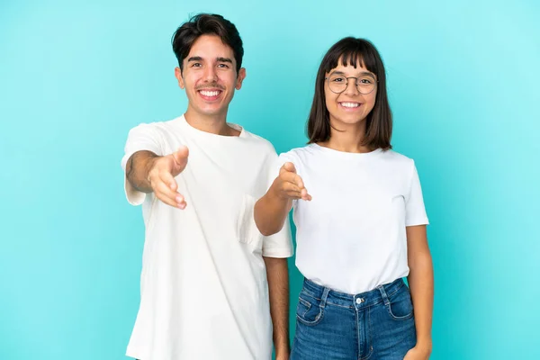 Junges Gemischtes Paar Isoliert Auf Blauem Hintergrund Schüttelt Hände Ein — Stockfoto