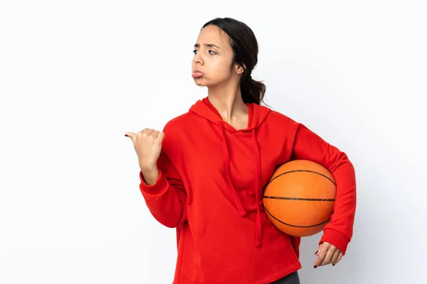 年轻女子在与世隔绝的白色背景下打篮球 心情很不高兴 她指着旁边 — 图库照片