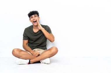 Genç Arjantinli adam yerde oturmuş ağzı açık bağırıyor.