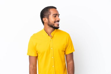 Genç Ekvadorlu adam beyaz arka planda izole edilmiş, yana bakıyor ve gülümsüyor.