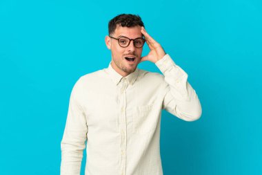 Mavi arka planda izole genç beyaz yakışıklı adam bir şey fark etti ve çözüme niyetlendi.