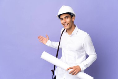 Genç mimar arka planda izole edilmiş. Davet etmek için ellerini yana uzatıyor.