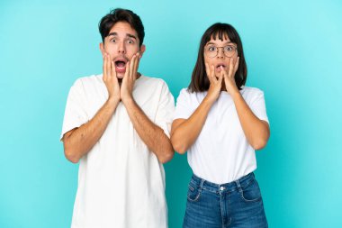 Mavi arka planda soyutlanmış genç melez çift sağa bakarken şaşırmış ve şok olmuştu.