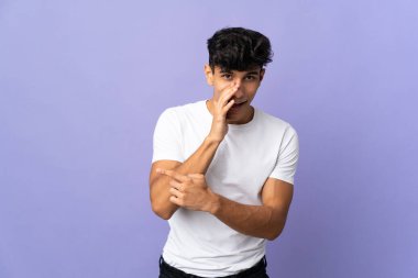 Arjantinli genç adam arka planda izole edilmiş bir şekilde bir ürün sunmak ve bir şeyler fısıldamak için kenarı işaret ediyor.