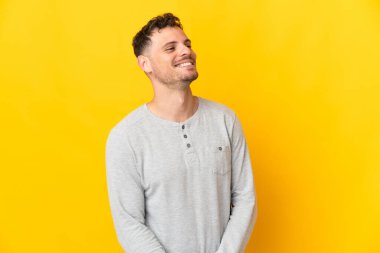 Sarı arka planda izole edilmiş beyaz, yakışıklı genç adam yana bakıyor ve gülümsüyor.