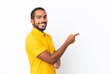 Genç Ekvadorlu adam beyaz arka planda izole edilmiş, parmağını yana doğru gösteriyor.