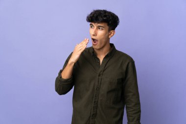 Arjantinli genç adam arka planda izole edilmiş esniyor ve ağzını eliyle açık tutuyor.