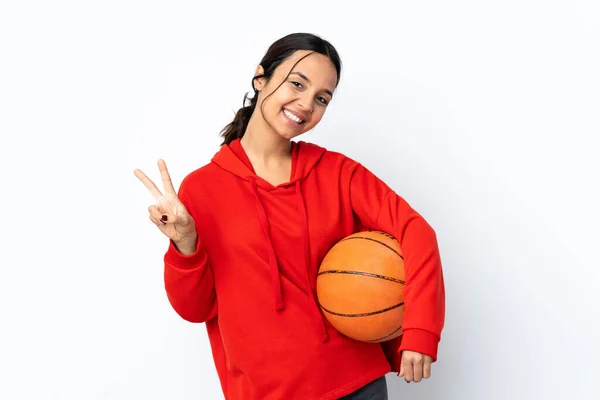 若いです女性遊びバスケットボール上の隔離された白い背景ショー勝利サインとともに手 — ストック写真