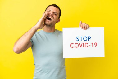 Mor arka plan üzerinde Brezilyalı bir adam elinde yazılı bir levhayla Covid 19 'u durdurun ve bağırın
