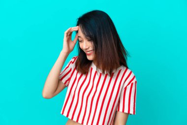 Genç Vietnamlı kadın mavi arka planda izole edilmiş gülüyor.