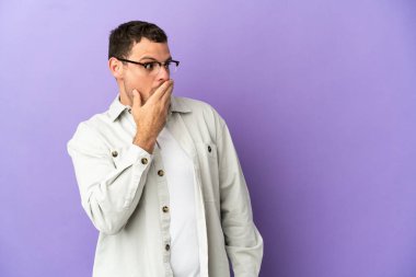 Mor arka planda kalan Brezilyalı adam yana bakarken sürpriz jest yapıyor.