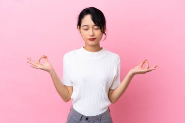 Genç Vietnamlı kadın Zen pozunda pembe arka planda izole edilmiş.