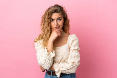 Pembe arka planda soyutlanmış genç sarışın kadın.