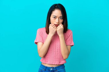 Genç Vietnamlı kadın mavi arka planda izole edilmiş gergin ve korkmuş bir şekilde elleriyle suni teneffüs yapıyor.