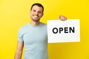 Mor arkaplan üzerine izole edilmiş Brezilyalı bir adam elinde mutlu bir ifadeyle açık bir pankart tutuyor.