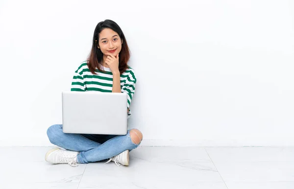 年轻的越南妇女 拿着笔记本电脑 坐在地板上 与白墙隔离 面带微笑 — 图库照片