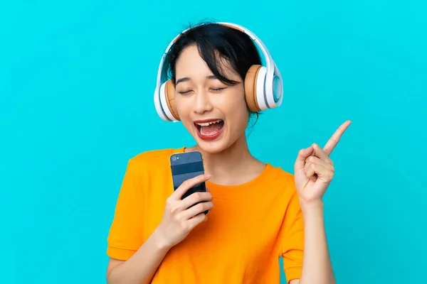 Mujer Vietnamita Joven Aislada Sobre Fondo Azul Escuchando Música Con — Foto de Stock