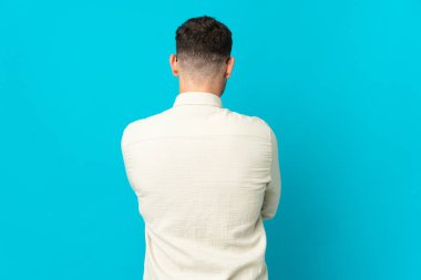 Kafkasyalı yakışıklı genç adam mavi arka planda izole edilmiş.