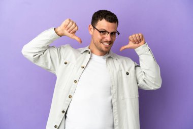 İzole edilmiş mor arka planı olan Brezilyalı adam gururlu ve kendini beğenmiş.