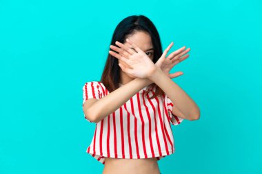 Genç Vietnamlı kadın mavi arka planda izole edilmiş, gergin ellerini öne doğru uzatıyor.