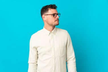 Beyaz tenli yakışıklı adam mavi arka planda izole edilmiş.