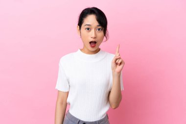 Pembe arka planda izole edilmiş genç Vietnamlı bir kadın bir fikir düşünüyor.