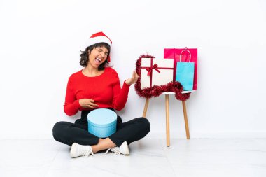 Genç bir kız Noel 'i kutluyor. Beyaz bir fırında tek başına oturmuş gitar jestleri yapıyor.