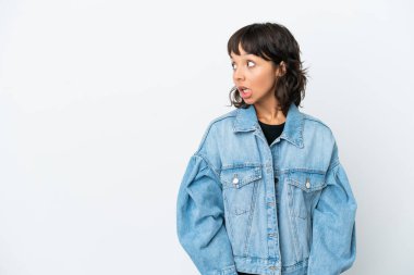 Beyaz arka planda izole edilmiş genç melez bir kadın. Yan tarafa bakarken sürpriz jest yapıyor.