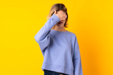 Sarı arka planda, gözleri elle kapatan genç bir Rus kadın. Bir şey görmek istemiyorum.