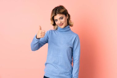 Pembe arka planda izole edilmiş genç bir Rus kadın baş parmak işareti yapıyor.