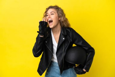 Sarı arka planda izole edilmiş motosiklet kasklı genç sarışın kadın ağzı sonuna kadar açık bağırıyor.