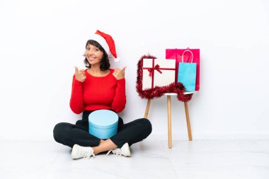 Genç bir kız Noel 'i kutluyor. Beyaz fırında yapayalnız oturuyor. Baş parmakları havada ve gülümsüyor.