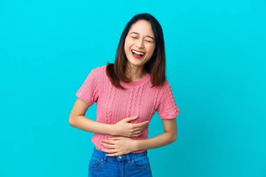 Genç Vietnamlı kadın mavi arka planda izole edilmiş, gülümsüyor.