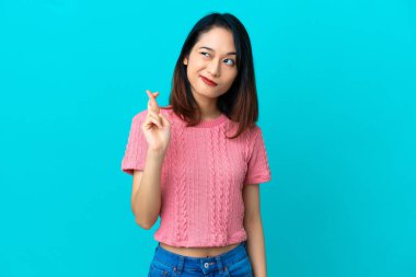 Genç Vietnamlı kadın mavi arka planda izole edilmiş, şans diliyor ve en iyisini diliyor.