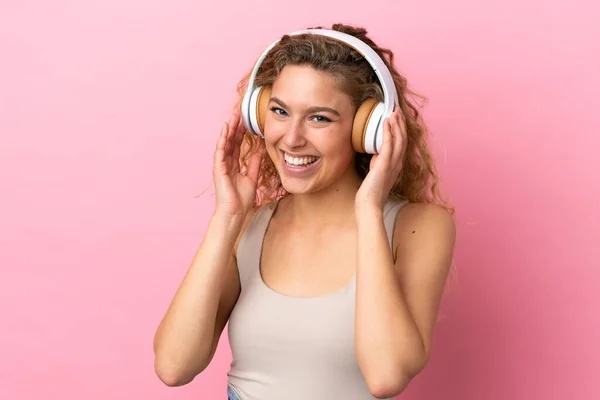 若いですブロンド女性絶縁上のピンクの背景リスニング音楽 — ストック写真