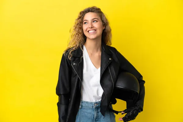 若いですブロンド女性とともにオートバイヘルメット隔離上の黄色の背景考え方Aアイデアながら見上げます — ストック写真