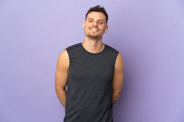 Mor arka planda yalnız, mutlu ve gülümseyen beyaz, yakışıklı genç bir adam.